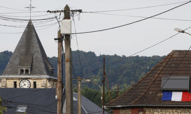 A French flag is seen on a rooftop near the bell tower of the church after a hostage-taking in Saint-Etienne-du-Rouvray near Rouen in Normandy, France, July 26, 2016. A priest was killed with a knife and another hostage seriously wounded in an attack on a church that was carried out by assailants linked to Islamic State. REUTERS/Pascal Rossignol